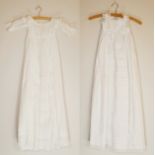 Two white christening gowns, one short sleeved with lace flower detailing around chest and at hem