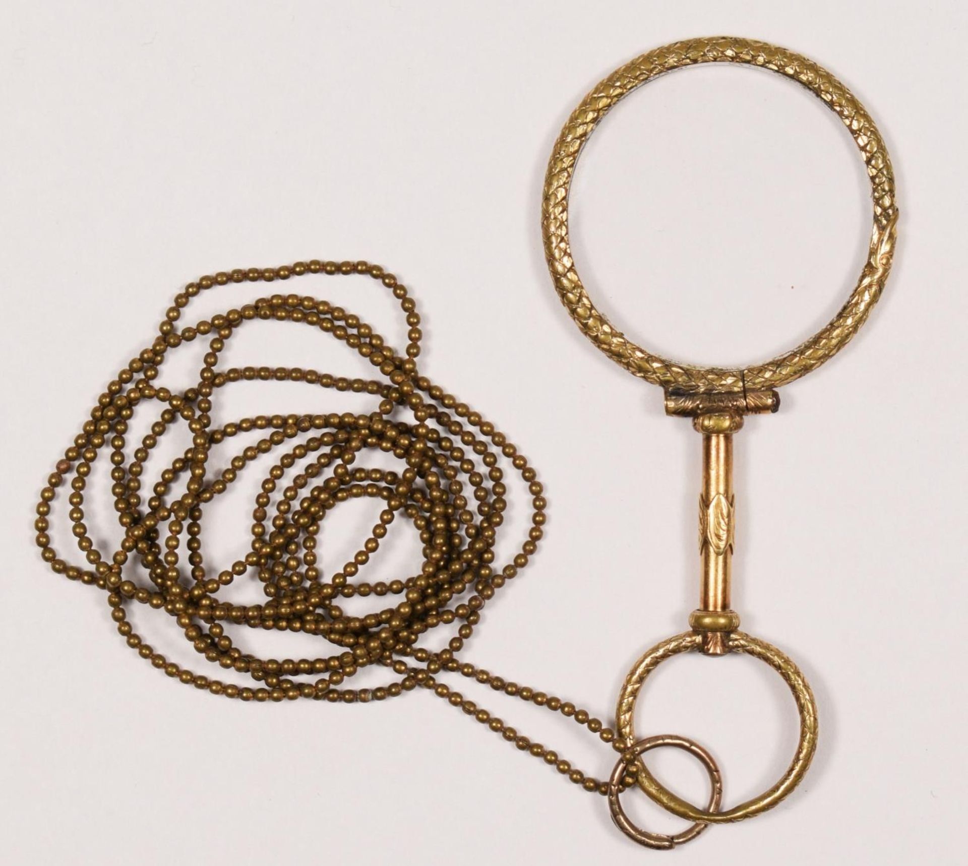 A Georgian gilt metal quizzing glass, with textured coiled snake frame, diameter 35mm.