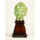 A carved green hardstone Buddha head lamp, mounted on a mahogany stand, 29cm.