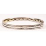 An 18ct white gold and brilliant cut diamond hinged bangle, channel set with two rows of 50 fifty