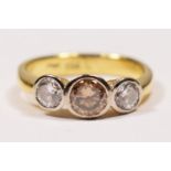 An 18ct gold three stone brilliant cut diamond ring, collet set with a champagne stone, estimated to