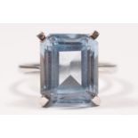 A white gold and synthetic blue spinel ring, tests as 18ct gold, claw set with an emerald cut stone,