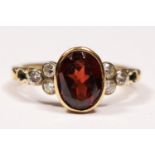 A 9ct gold, garnet and brilliant cut diamond ring, collet set with an oval mixed cut stone,