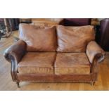 A tan leather two seater sofa, with feather back cushions, 149 x 76 x 82cm