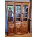 A pine three door bookcase cabinet, three glazed doors over three drawers over three cupboard doors,