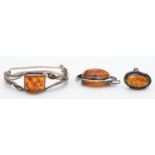 A silver set amber bangle, a silver set amber brooch and ring, 54g.