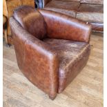 A tan leather tub armchair