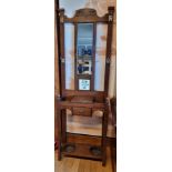 An Edwardian oak hall stand, having mirrorback over central drawer on square tapered legs with lower