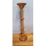 A solid light oak jardinière/plant stand, having turned column on a round stepped base. H99cm.