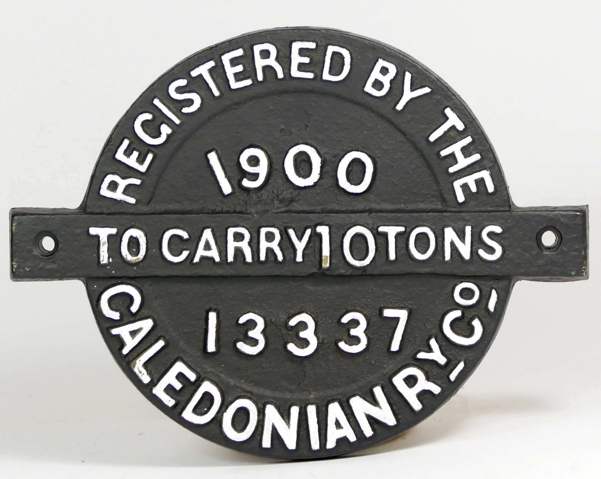 A round cast iron wagon plate, 'Caledonian Ry. Co. 1900, To Carry 10 Tons No. 13337'.