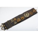 A collection of 13 military cap badges, mounted on a belt to include Australian , 9th Lancers and