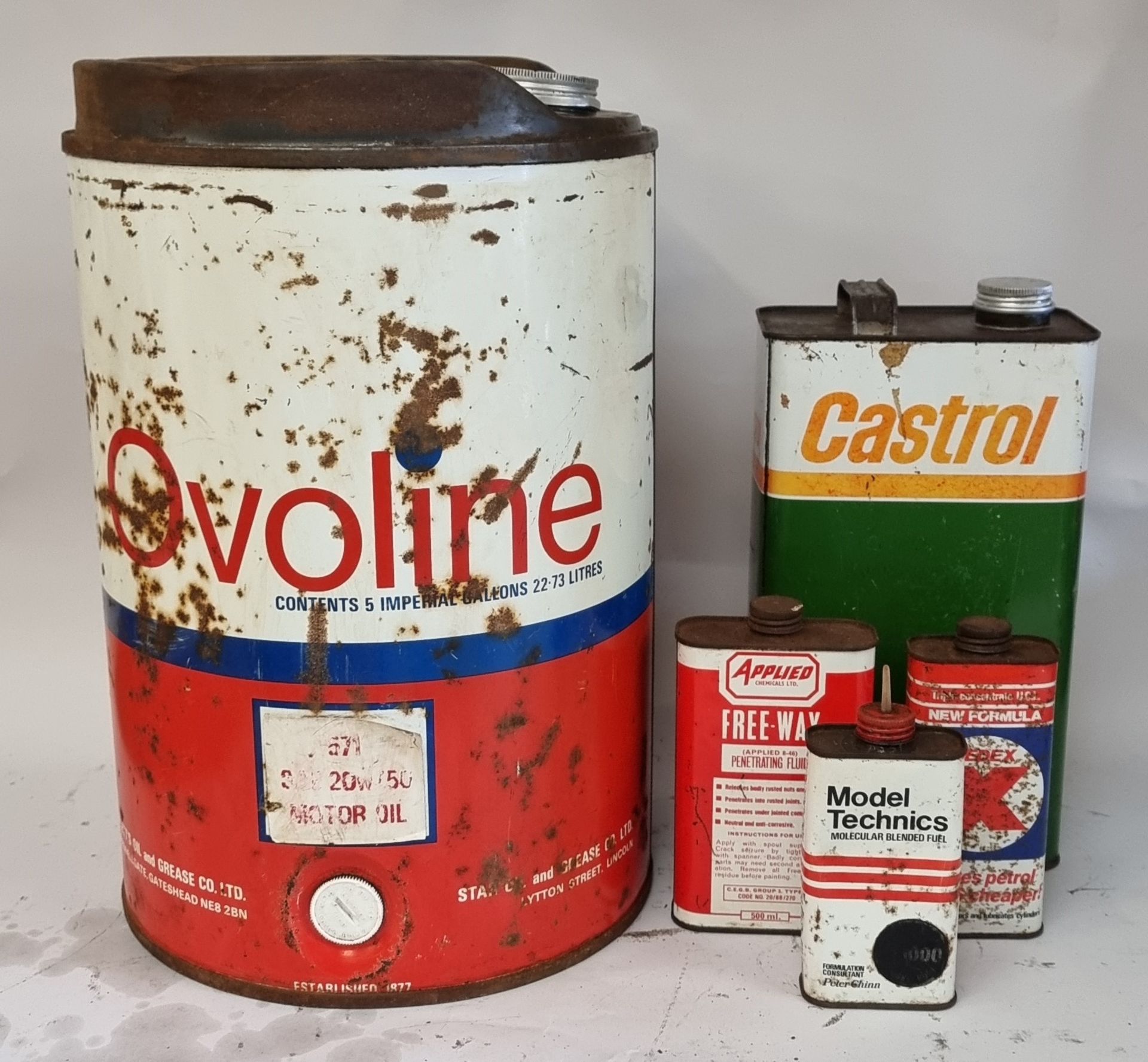 An Ovoline 5 gallon can, Castrol 1 gallon can and three other cans