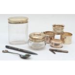 Four silver napkin rings, a silver pencil, two silver topped jars, a silver cased penknife and an