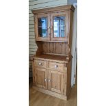 A pine kitchen dresser, glazed upper, hinged doors open to reveal a single shelf, above two small