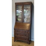 A late 19th / early 20th century oak bureau, glazed upper display cabinet, lead fronted hinged doors