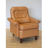 A tan leather armchair by Tetrad of London, having padded seat and backrest, angled arms, on squared