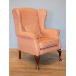 A modern wing back armchair, upholstered in a muted pink fabric, on cabriole legs, 75 x 110 x 70cm