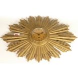 An Art Deco inspired wall clock, starburst form, carved wooden body with gilt decoration, gilt