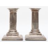 A Victorian silver pair of Corinthian column desk candlesticks, Sheffield 1890, raised on beaded