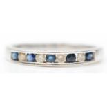 A 9ct white gold sapphire and diamond nine stone ring, channel set with brilliant cut stones, stated