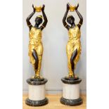 An impressive pair of cast bronze female Blackamoor torcheres, the ladies in gilt dresses holding