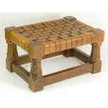 A Robert 'Mouseman' Thompson footstool, having cowhide interwoven strap top, supported by carved