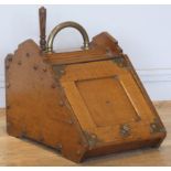 An Edwardian oak coal scuttle, the panelled fall-front with brass handles and mounts, complete metal