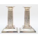 A Victorian silver pair of Corinthian column desk candlesticks, London 1900 raised on beaded