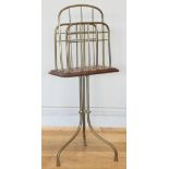 An Edwardian rotating magazine rack, the brass tripod base with mahogany and with three brass