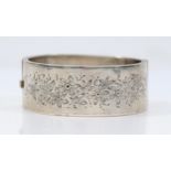 A Victorian silver hinged bangle, Birmingham 1885, with floral engraved decoration 25mm wide,