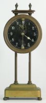 A British made brass gravity clock, the glass face with painted numerals, inside is a pendulum on