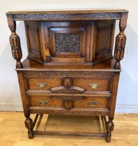 An Edwardian oak court cupboard with inlaid carved foliate detail, the upper section fitted with
