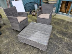 A rattan garden patio low table with glass top and two armchairs