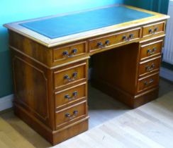 A modern yew wood twin pedestal desk, the top with inset leather skiver above two banks of three