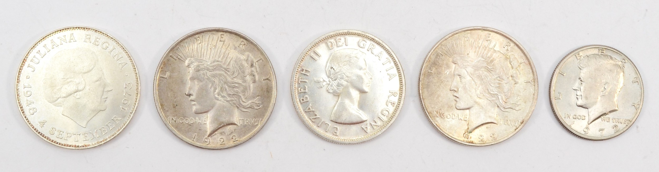 Two 1922 silver low relief peace dollars, a 1972 Kennedy half dollar, a silver Canadian totem pole