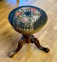 A Victorian carved walnut piano stool with adjustable revolving seat height, upholstered tapestry