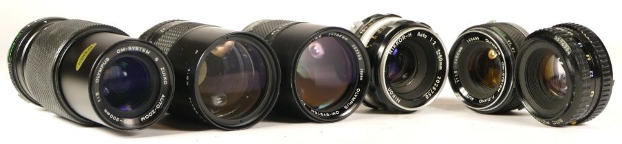 Six assorted camera lenses to include three Olympus camera lenses (mechanically working but requires