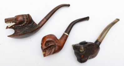 Three 20th century carved Black Forest style pipes, the bowls carved in the form of a skull,