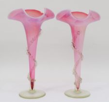 A pair of late 19th/early 20th red vaseline trumpet shaped vases, each with applied clear glass swag