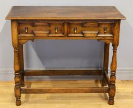 An early 20th century oak Jacobean style twin panelled drawer low boy, each with brass drop