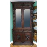 A 19th century heavily carved oak corner cupboard, with two glass doors opening to reveal three