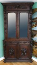 A 19th century heavily carved oak corner cupboard, with two glass doors opening to reveal three