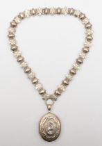 A Victorian unmarked silver locket and collar necklace, the locket with chased floral and embossed