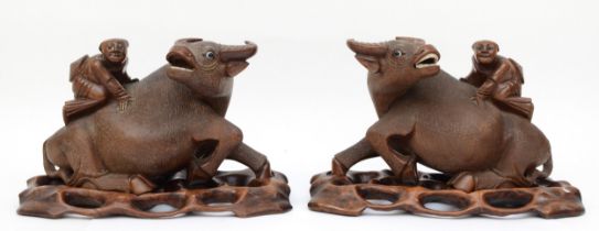 A pair of 20th century Chinese carved hardwood water buffalo with boys riding their back, each