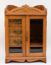 An early 20th century golden oak twin glass door table top smokers cabinet, opening to reveal pipe