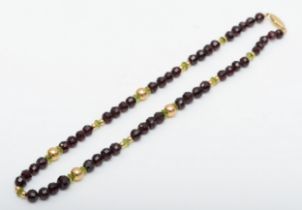 A 14k gold clasped garnet and peridot beaded necklace, 7 - 5mm beads, 39.5gm.