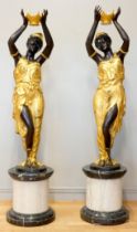 An impressive pair of cast bronze female Blackamoor torcheres, the ladies in gilt dresses holding