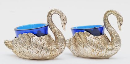 A pair of German silver swan condiments, 800 standard with Crown, articulated wings, blue glass