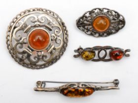 Four silver mounted amber brooches, 25gm