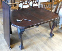 An Edwardian mahogany wind out dining table, of oval form raised on claw and ball feet, with extra